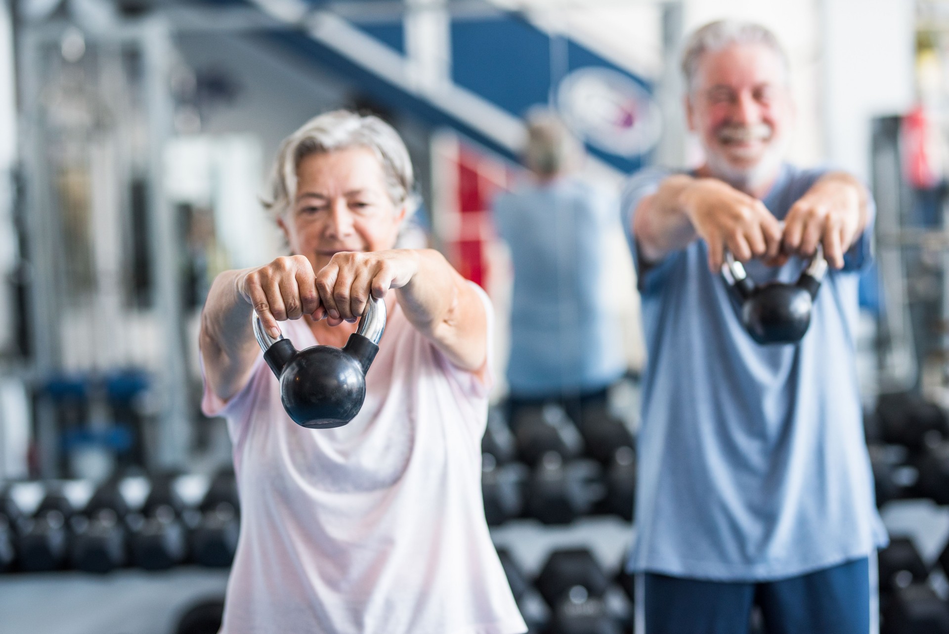 couple of two happy and fitess seniors doing exercise in the gym together running on the tapis roulant - active lifestyle